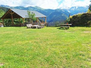 a gazebo with benches in a field with mountains at Heshklar guest house in Keshkili