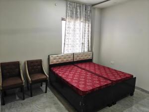 a small bedroom with a bed and two chairs at Diksha Heritage In in Prayagraj +1 photo