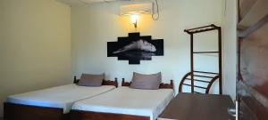 two beds in a room with a ladder and a picture on the wall at Hansika Guest Inn in Buttala