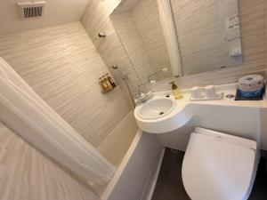 a white bathroom with a toilet and a sink at le Lac Hotel Yokkaichi in Yokkaichi