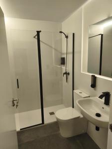 a white bathroom with a toilet and a sink at Albergue O Centro in Portomarin +7 photos