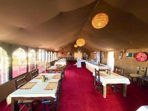 a dining room with tables and chairs and windows at Erg Chebbi Dunes Desert Camp in Merzouga