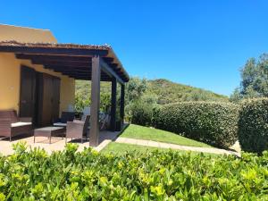 a patio with a table and chairs in a garden at Rosanna House in Bombarde Beach in Alghero