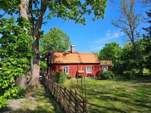 a red house with a fence and a tree at Tolvmansgården in Enköping