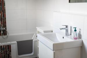a white bathroom with a sink and a bath tub at Seelenruhe in Goch +4 photos