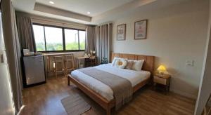 a hotel room with a bed and a window at Charming Home Resort in Suan Phung