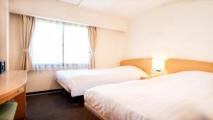 a hotel room with two beds and a window at le Lac Hotel Yokkaichi in Yokkaichi