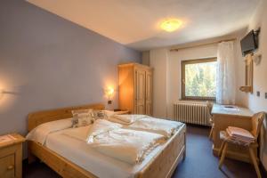 a bedroom with a bed and a desk and a window at Hotel Canada in Predazzo