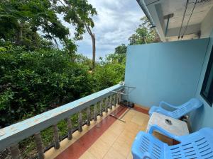 two blue chairs on a balcony with trees at Tommy Apartment - main road in Ko Tao
