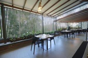 a restaurant with tables and chairs and large windows at Ynad Mount Resort in Meppādi