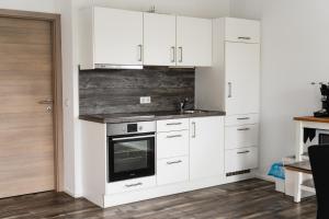 a white kitchen with white cabinets and a tv at Fewo 14 DG in Goch