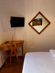 a bedroom with a bed and a desk with a television at Albergo Brustolon in Dont