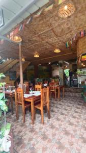a restaurant with wooden tables and chairs in a room at TAGBALAYON-GARDEN Guest House in Siquijor