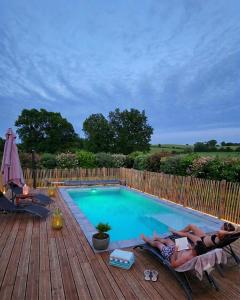 two people laying on chairs next to a swimming pool at La Lézardière in Pleugriffet