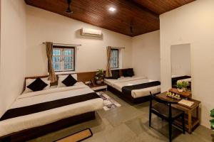 a hotel room with two beds and a table at Shalimar in the Forest in Matheran