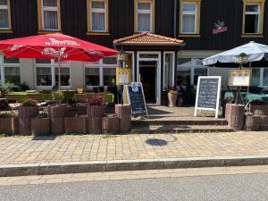 ein Restaurant mit Tischen und Sonnenschirmen vor einem Gebäude in der Unterkunft Ferienhotel Forelle Thale Ortsteil Treseburg in Thale
