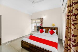 a bedroom with a bed with red pillows and a window at Hotel O Dream Marion in Bhubaneshwar