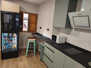 a kitchen with a refrigerator and a microwave at Albergue O Centro in Portomarin
