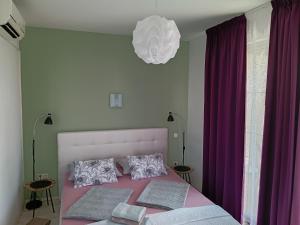 a bedroom with a pink bed with purple curtains at Ana Rooms in Krk