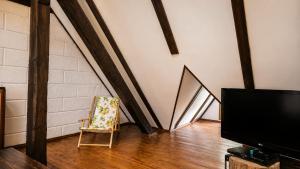 a living room with a tv and a chair at Duplex U Marzeny in Ostróda