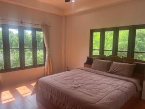 a bedroom with a bed in a room with windows at theorenda 002 in Koh Samui