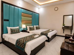 a hotel room with two beds and a mirror at Galaxy Inn Guest House in Karachi