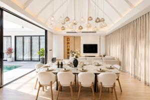 a dining room with a table and chairs and a couch at Le Da Villas 5BR Bang Tao Beach in Laguna Phuket