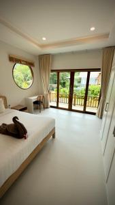 a bedroom with a bed and a desk and windows at Canal Villa in Chaloklum