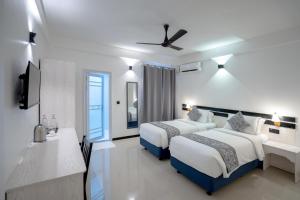 a hotel room with two beds and a television at Cozy Roots Fuvahmulah in Fuvahmulah