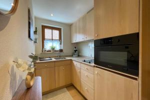 a kitchen with wooden cabinets and a black appliance at Ferienwohnung Bergleuchten in Obermaiselstein