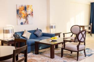a living room with a blue couch and chairs at Sedra Arjaan by Rotana in Doha +33 photos