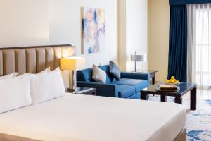 a hotel room with a bed and a blue couch at Sedra Arjaan by Rotana in Doha