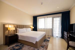 a bedroom with a bed and a large window at Sedra Arjaan by Rotana in Doha