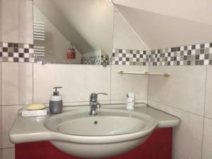 a white sink in a bathroom with checkered tiles at Logis des Brousses in Lhommaizé