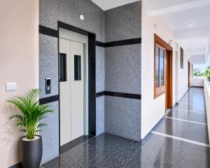 a hallway with black and white walls and a potted plant at SLS Homestay - Luxury AC Service Apartments 1BHK, 2BHK, 3BHK - Direct Flyover to Alipiri Tirumala Gate - Walk to PS4 Pure Veg Restaurants, Supermarkets - Near to National Highway & Padmavathi Amma Temple - Modular Kitchen, Living room -Free Superfast Wifi in Tirupati +5 photos