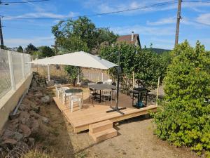 a wooden deck with a table and an umbrella at L'écrin d'Hélène in Lormes