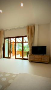 a living room with a flat screen tv and a large window at Canal Villa in Chaloklum