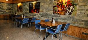 a dining room with wooden tables and blue chairs at Foresta Living Kasol in Kasol +148 photos