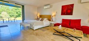 a bedroom with a bed and a red couch at PETIT PARADIS 24 in Groléjac