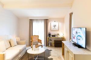 a living room with a couch and a tv at Mas des Herbes Blanches Hôtel & Spa – Relais & Châteaux in Joucas