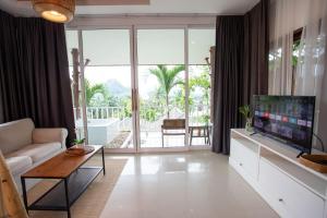 a living room with a television and a couch and a table at Baan Phuvara Retreat - Romantic Jacuzzi Mountain View Villas in Ao Nang Beach