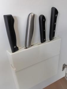 a white shelf with four knives on it at MATAHARI Guest house in Miyazaki
