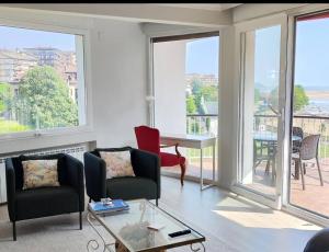 a living room with chairs and a table and windows at Urdaibai Luxy in Pedernales