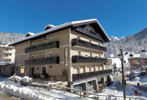 un gran edificio con nieve en el suelo en Hotel Garni Arnica ***S en Madonna di Campiglio