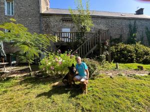a woman with a dog sitting in the grass at Le Manoir de Gourvinec in Saint-Nolff