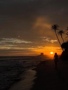 a woman walking on the beach at sunset at Mukalawatta Villa in Matara +2 photos