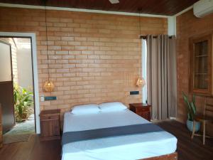 a bedroom with a bed and a brick wall at Mukalawatta Villa in Matara