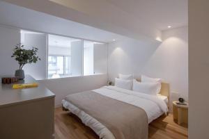 a white bedroom with a large bed and a window at base-WENDING Service Apartment-Shanghai Xujiahui Location in Shanghai
