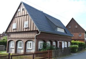 a house with a gambrel roof with a fence at Ferienhaus Elsa mit Sauna und Whirlpool in Großschönau
