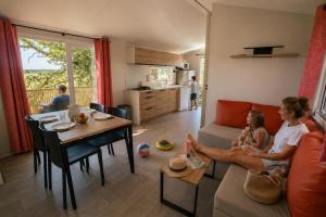 a woman and a child sitting on a couch in a living room at Camping Paradis d'Arvor in Ambon